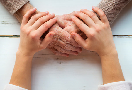 Unrecognizable grandmother and her granddaughter holding hands.