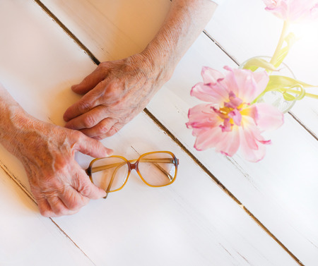 Hands of unrecognizable senior woman holding glassesの写真素材