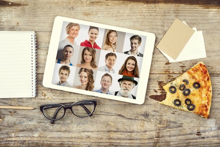 Desktop mix with office gadgets, supplies and pizza on a wooden office table background. View from above.の写真素材