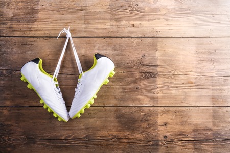 Pair of sneakers hang on a nail on a wooden fence backgroundの写真素材