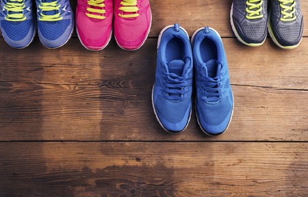 Four pairs of various running shoes laid on a wooden floor backgroundの写真素材
