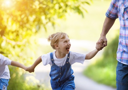 Happy little girl having fun with her family in green nature.の写真素材
