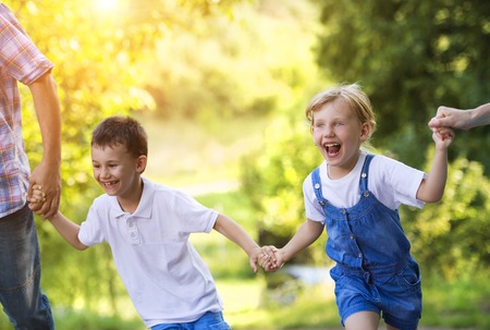 Happy little girl and boy having fun with their parents in green nature.の写真素材