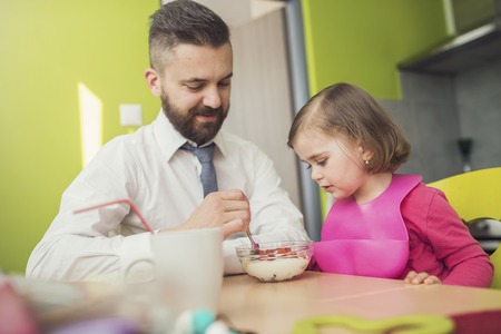 Young father feeding his little daughterの写真素材