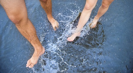 Unrecognizable woman and man walking barefoot through a puddleの写真素材