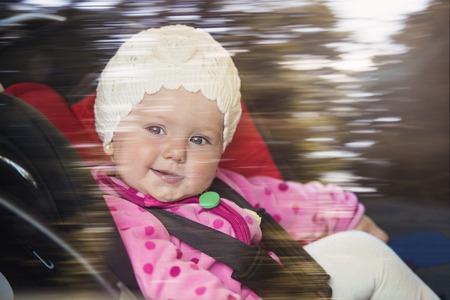 Little baby girl in a car in a child seatの写真素材