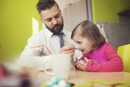 Young father feeding his little daughterの写真素材