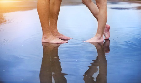 Unrecognizable woman and man standing barefoot in a puddleの写真素材