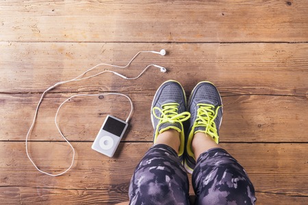 Unrecognizable young runner sitting on a floor. Studio shot on wooden background.の写真素材