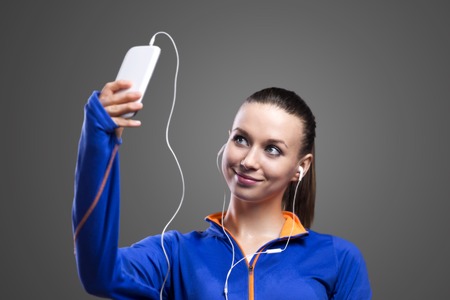 Young runner taking a selfie. Studio shot on a gray background.の写真素材