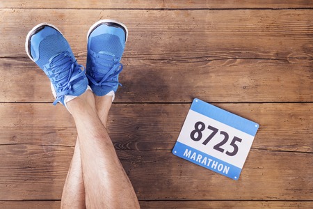 Legs of a runner and race number on a wooden floor background