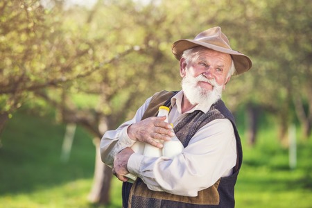 Senior farmer with milk bottles outside in green natureの写真素材