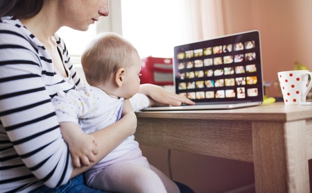 Young mother in home office with computer and her daugherの写真素材