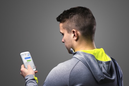 Young runner with smart phone. Studio shot on gray background.の写真素材