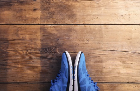 Pair of blue running shoes laid on a wooden floor backgroundの写真素材