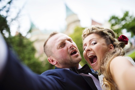 Young wedding couple taking a selfie of themselves as they enjoy romantic moments in front of a castleの写真素材