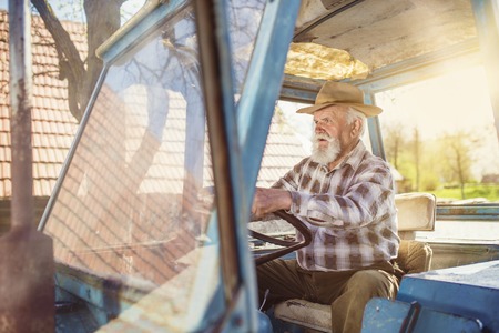 Senior man at the farm driving an old tractorの写真素材