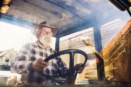Senior man at the farm driving an old tractorの写真素材