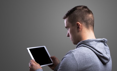 Young runner with a tablet. Studio shot on gray background.の写真素材