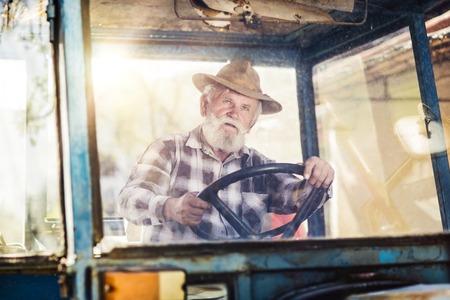 Senior man at the farm driving an old tractorの写真素材