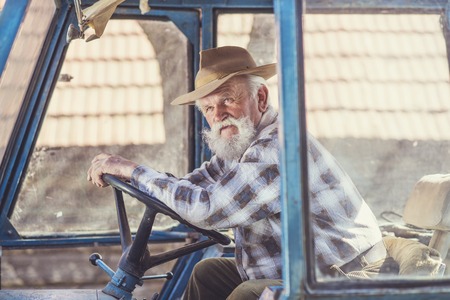 Senior man at the farm driving an old tractorの写真素材