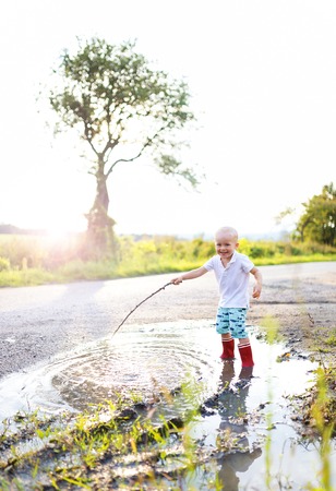 Little boy playing outside in a puddleの写真素材
