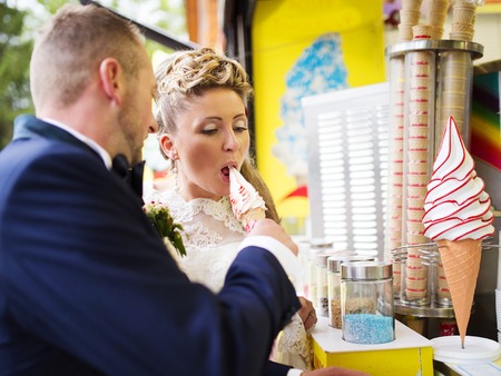 Beautiful young wedding couple enjoying ice creamの写真素材