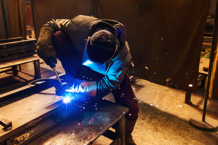 Young man with protective mask welding in a factoryの写真素材