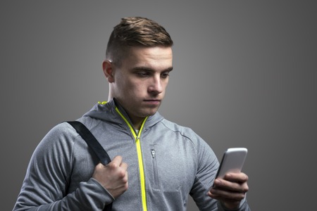 Young runner with smart phone. Studio shot on gray background.の写真素材