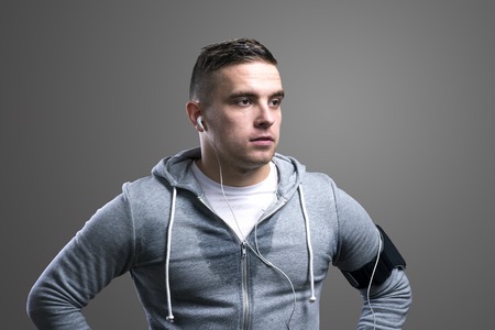 Young runner with headphones. Studio shot on gray background.の写真素材
