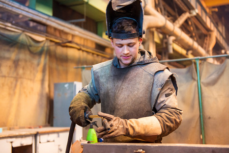 Young man with protective mask welding in a factory