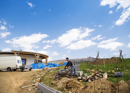 Bricklayer taking another brick from a wheelbarrowの写真素材