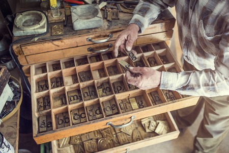 Senior man holding a letter that is used for engravingの写真素材