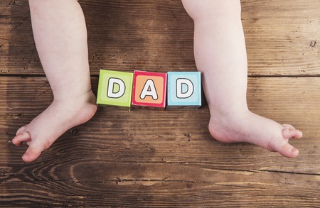 Little baby with cubes with dad sign on wooden の写真素材