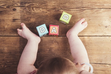 Little baby with cubes with dad sign on wooden backgroundの写真素材