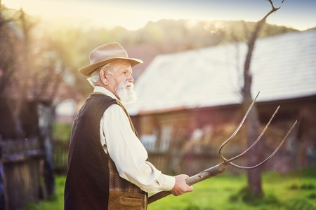Old farmer with pitchfork taking a break from workの写真素材