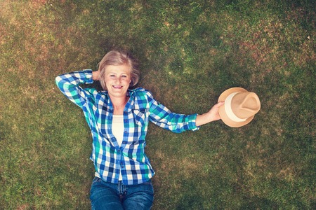 Beautiful senior woman lying on a grass in a park