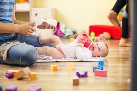 Young hipster father changing nappy to his little baby daughterの写真素材