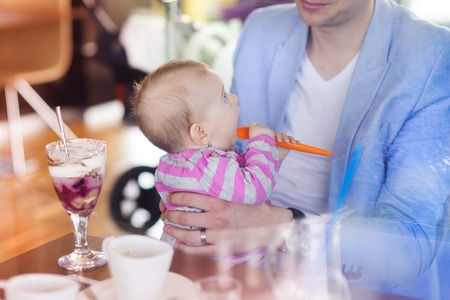 Young father with his cute baby daughter in cafeの写真素材