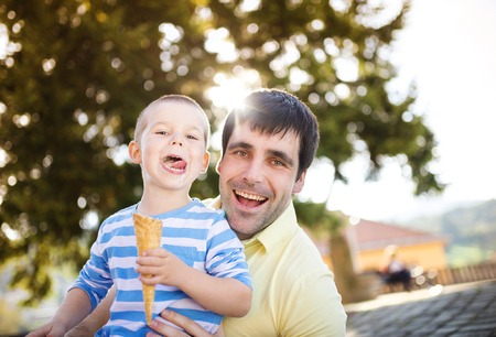 Father and son enjoying ice cream outside in a parkの写真素材