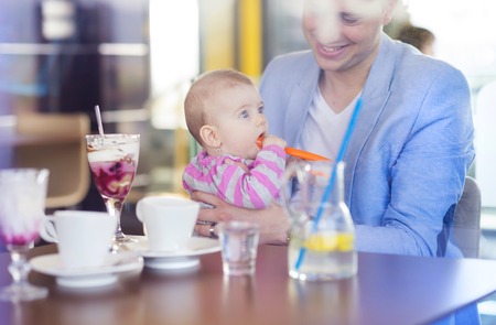 Young father with his cute baby daughter in cafeの写真素材