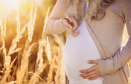 Portrait of beautiful pregnant woman in a fieldの写真素材