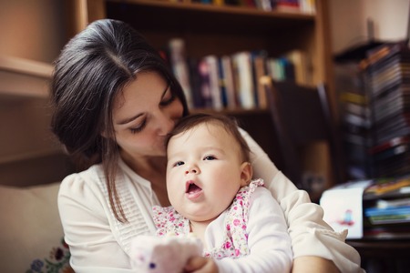 Mother with her baby daughter in the living roomの写真素材
