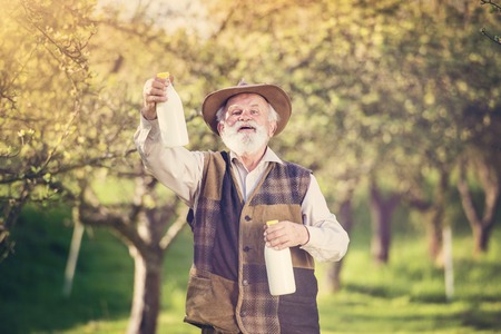 Senior farmer with milk bottles outside in green natureの写真素材
