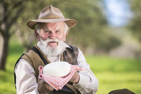 Senior farmer with organic cheese outside in green natureの写真素材