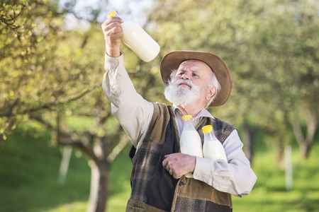 Senior farmer with milk bottles outside in green natureの写真素材
