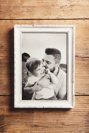 Fathers day composition - picture frame with a black and white photo. Studio shot on wooden background.の写真素材