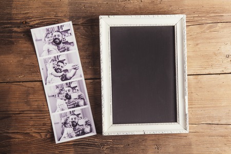 Picture frame and instant photos on wooden background.