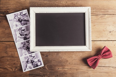 Picture frame, instant photos and a bow tie on wooden background.の写真素材
