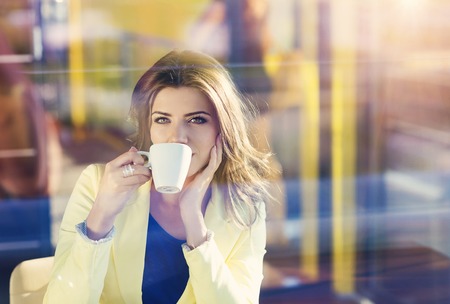 Attractive young woman sitting in cafe drinking coffeeの写真素材